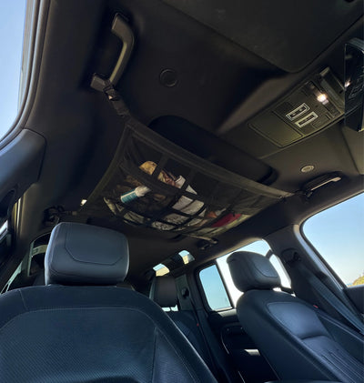 Overhead car cargo net installed with lightweight blankets and jackets